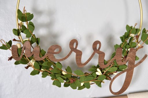 scandinavian christmas mantel closeup of wreath with greenery and word Merry