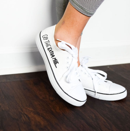White tennis shoes with text on the side "Go the Extra Mile" perfect for Spring.
