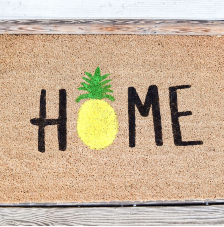 Doormat made with freezer paper technique. Says HOME with a pineapple in place of the O