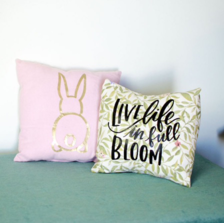 Gold bunny on a pink pillow and another pillow with a word Live Life in Full Bloom