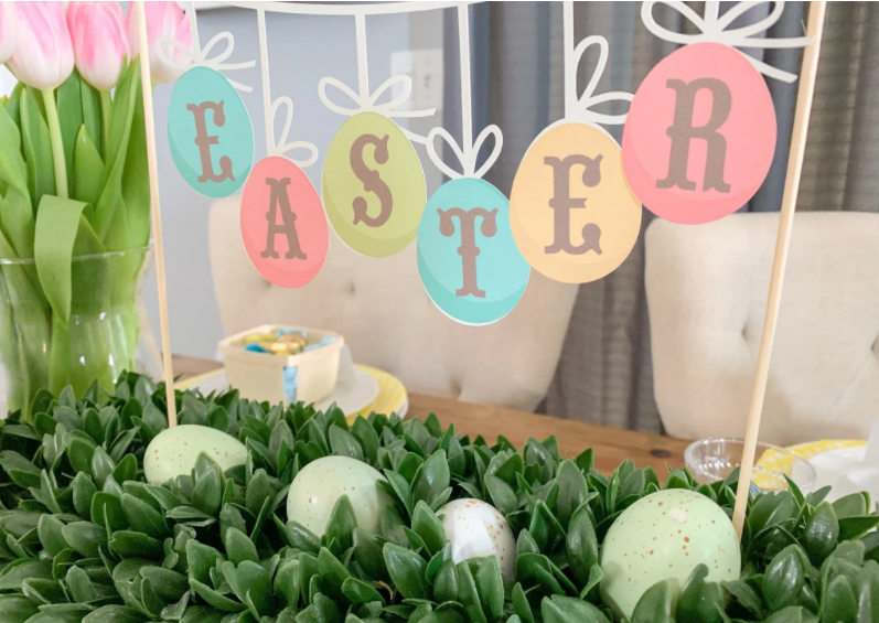 Easter Egg Shapes spelling out the word EASTER hung like bunting from dowels for table centerpiece
